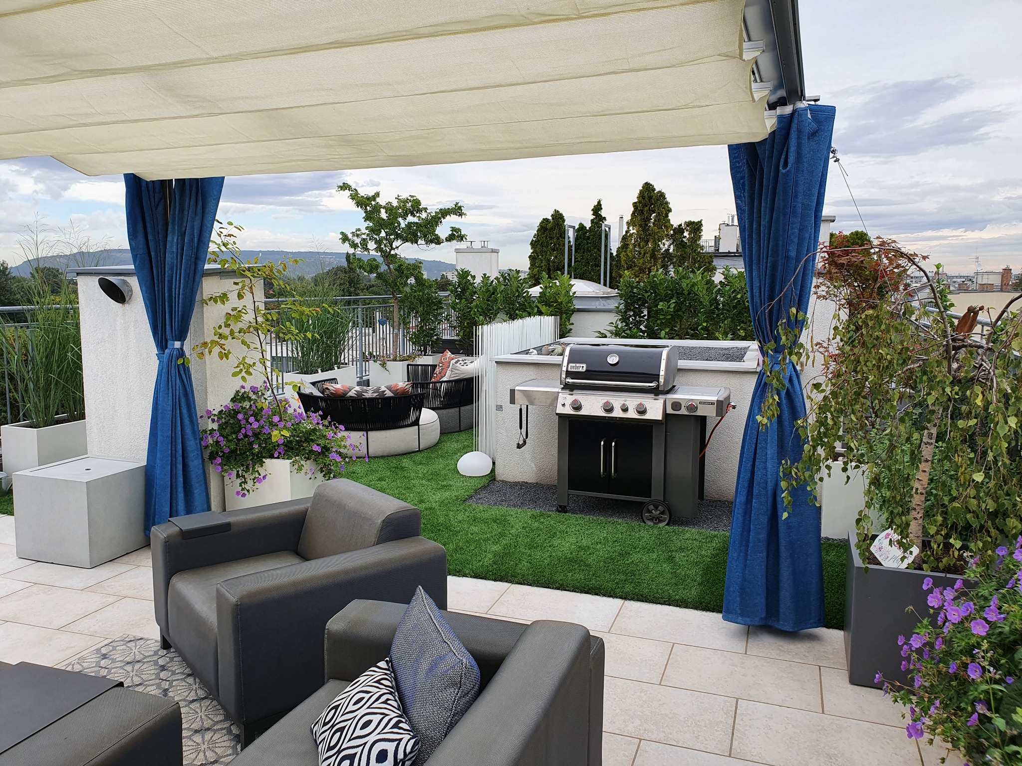 Realisierte Dachterrassengestaltung in Wien mit Grillplatz, Pflanztrögen, Natursteinbelag und begrüntem Ruhebereich
